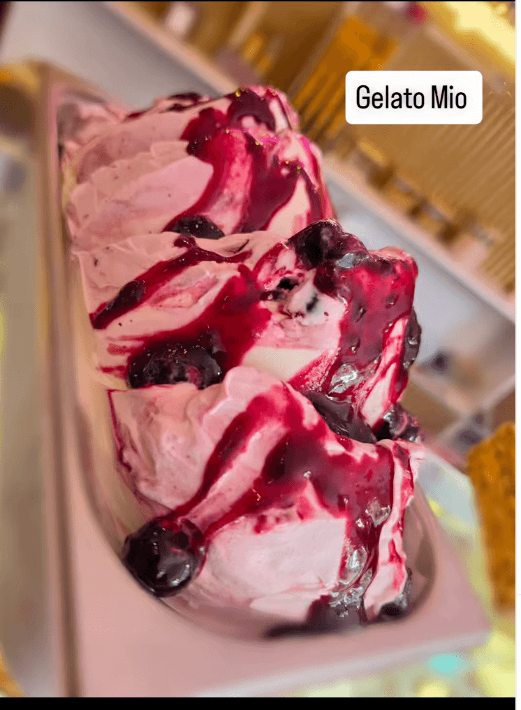 Bak gelato met dieprode bosvruchtensaus en hele bessen in de vitrine van Gelato Mio