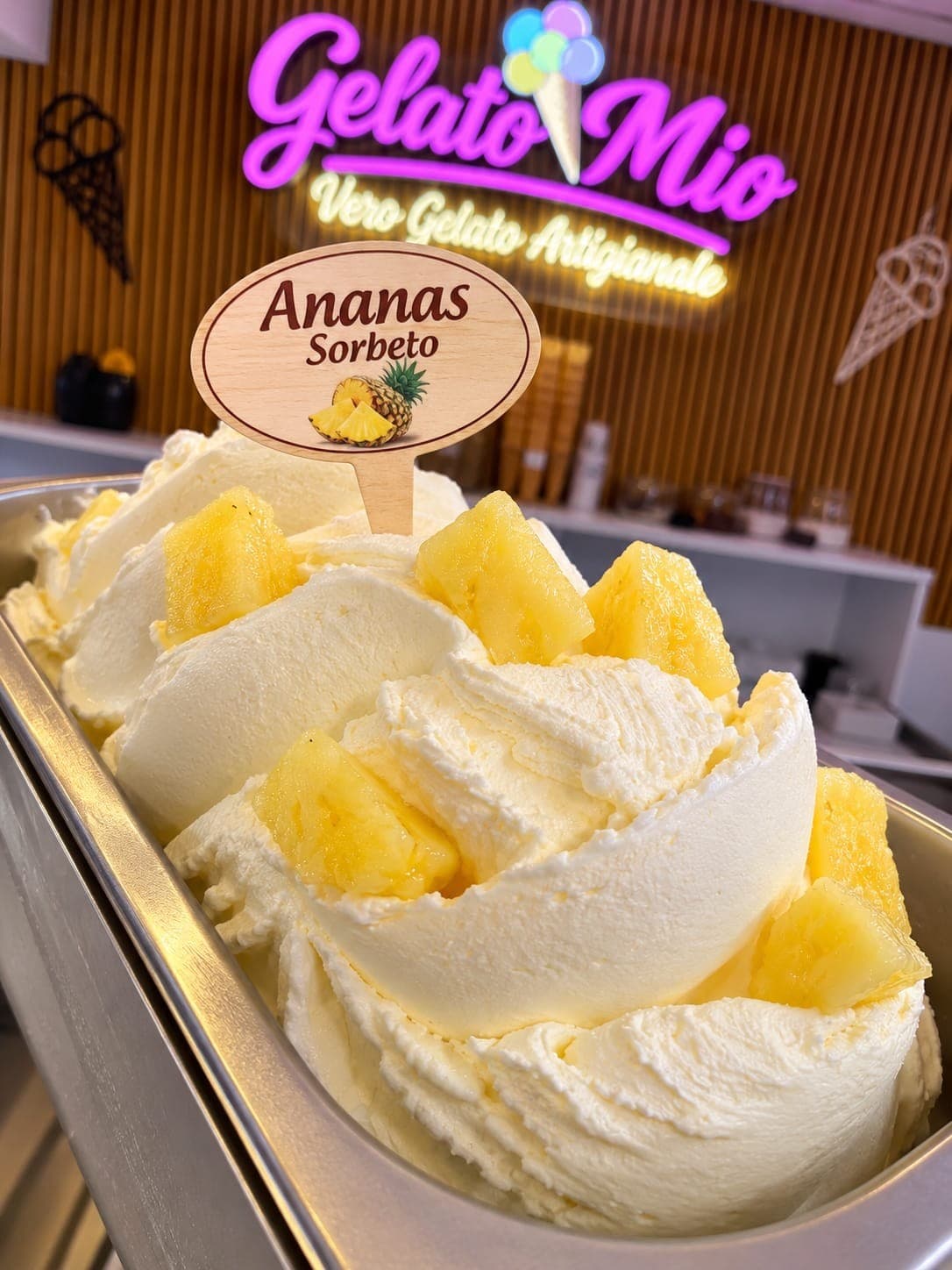 Bak lichtgele ananassorbet met stukjes verse ananas