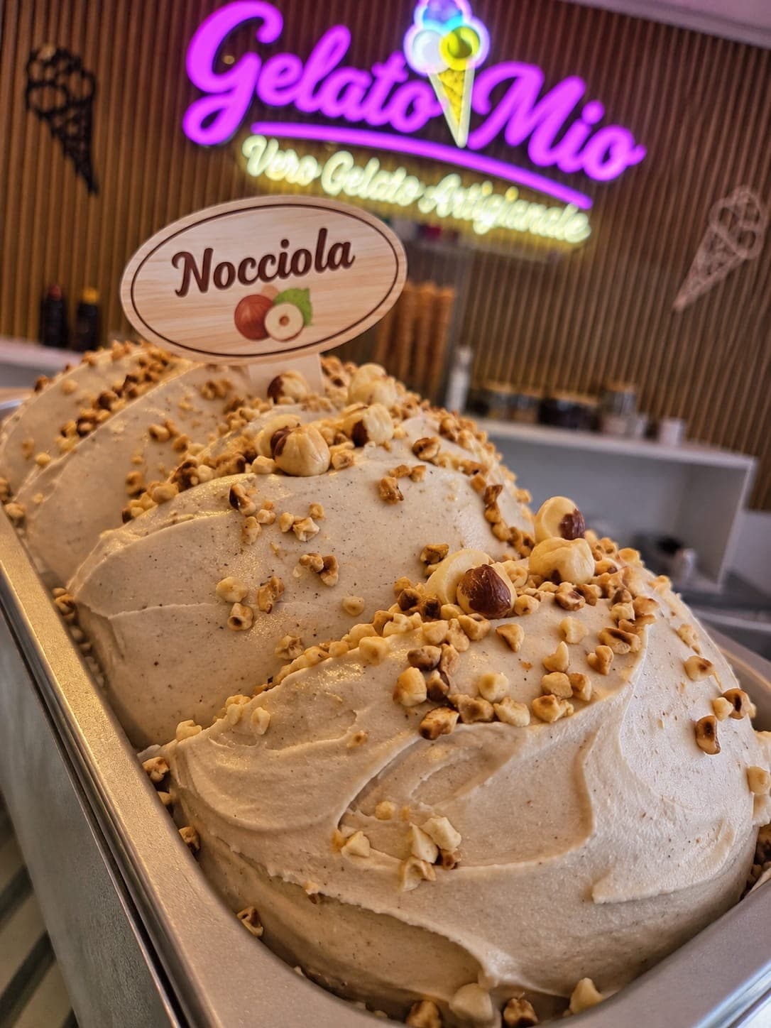 Bak hazelnootgelato bestrooid met gehakte en hele hazelnoten