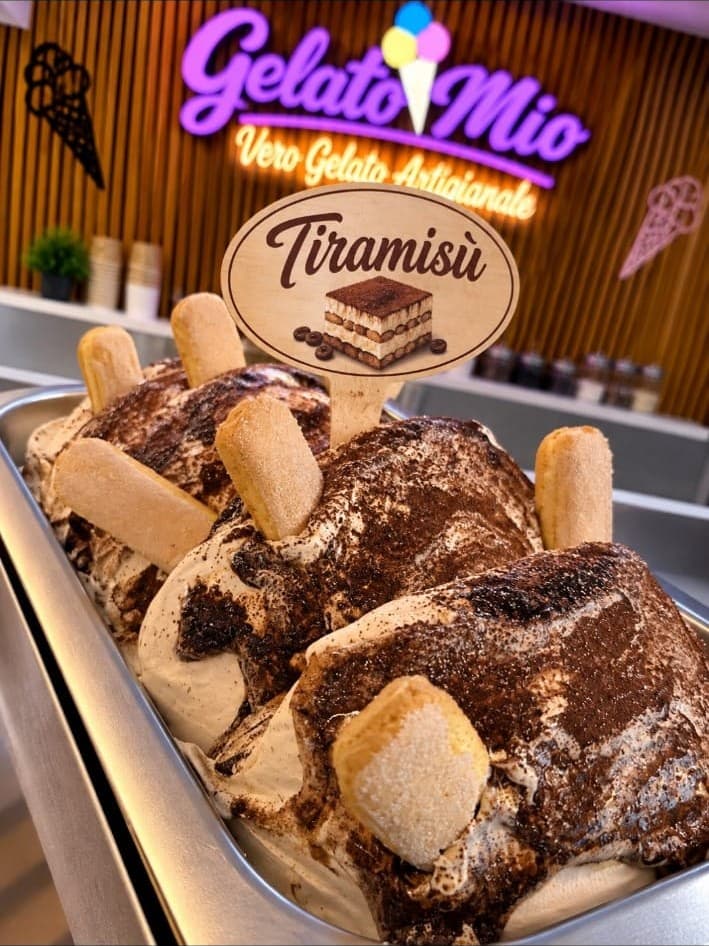 Bak tiramisù-gelato met cacao en lange vingers voor het neonlogo van Gelato Mio