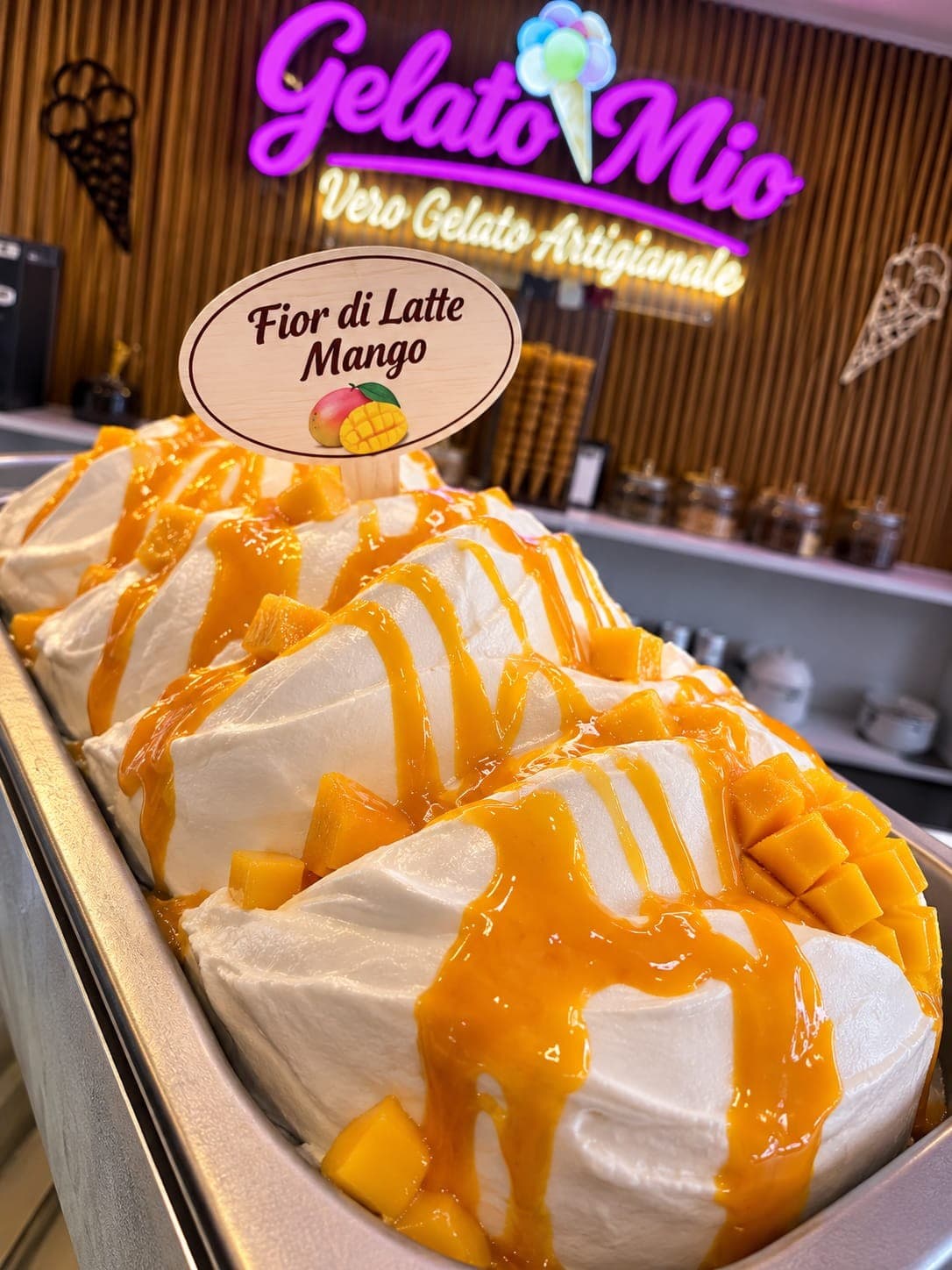 Bak wit fior di latte-gelato met mangoblokjes en oranje mangosaus