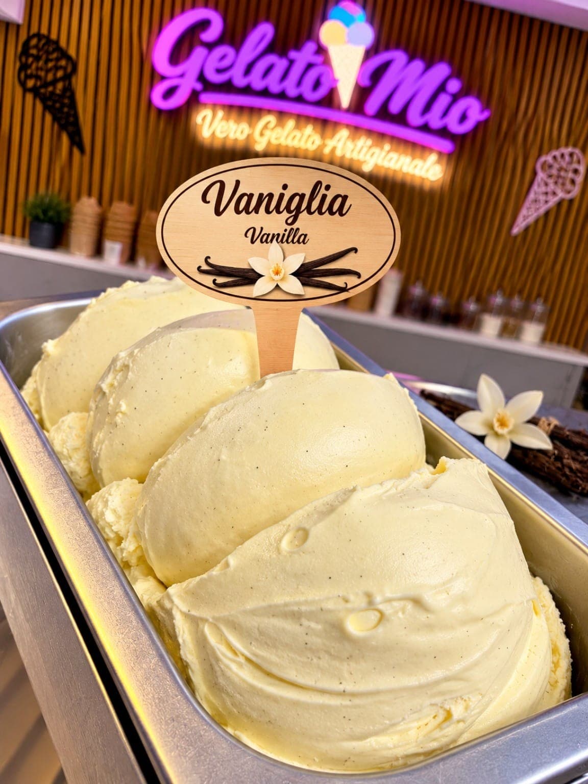 Bak lichtgeel vanillegelato met vanillezaadjes en een vanillebloem bij Gelato Mio